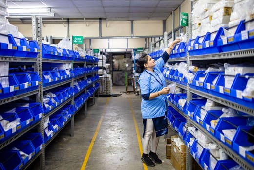 A distribution center worker picking from labeled bins