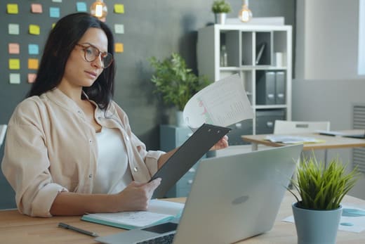A procurement specialist reviewing a document at her desk