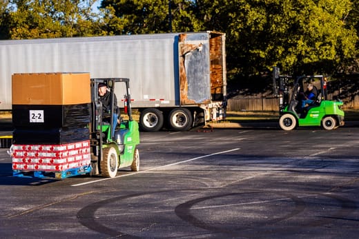 A forklift carrying a pallet past a semi-trailer, for the logistics degrees ranking