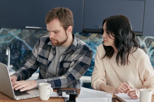 Two people going over bills at a laptop, for the most affordable online degrees