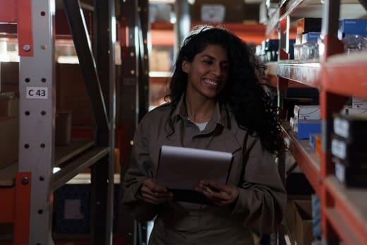 A smiling worker with a tablet in a warehouse aisle