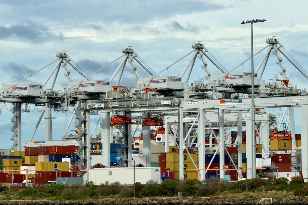 Ship-to-shore cranes over rows of stacked containers at a waterfront container terminal