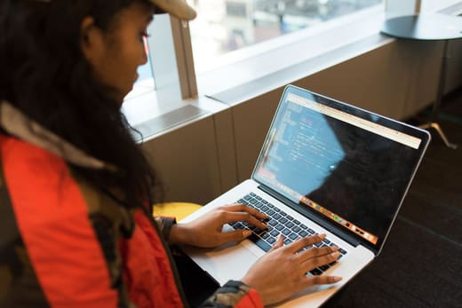 A woman writing code on a laptop, for operations research analyst pay