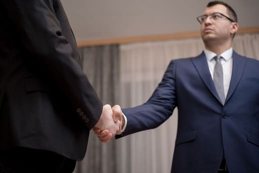 A handshake closing a business meeting, for purchasing manager pay