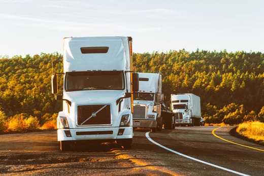 Semi trucks in convoy on a highway, for transportation manager pay