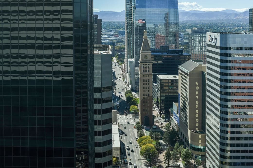 A downtown of glass towers around a domed clock tower, seen from the air