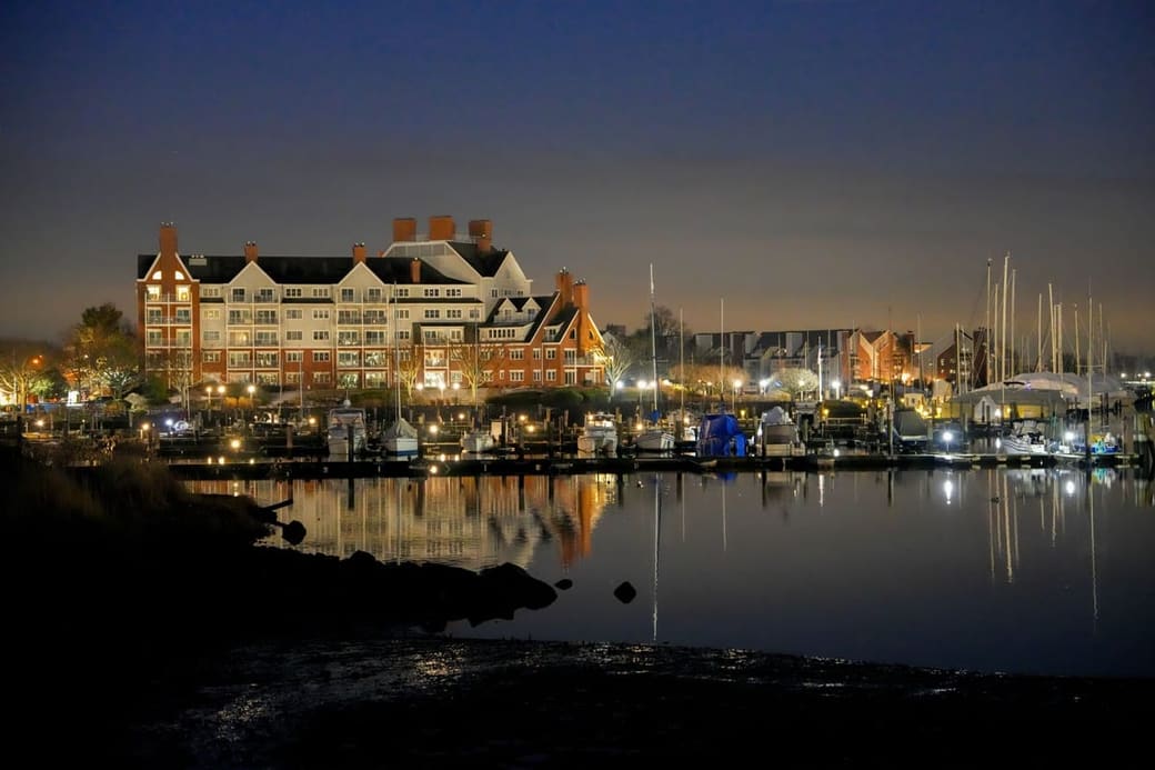 Office buildings above a marina of moored sailboats at twilight