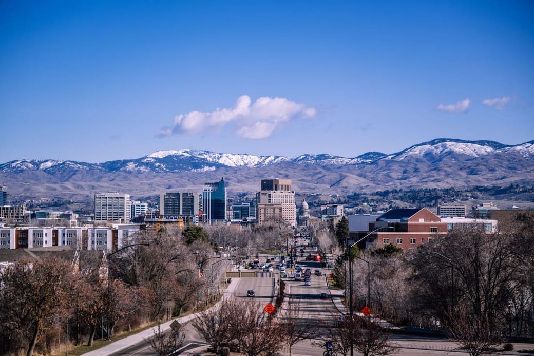 A compact downtown of mid-rise buildings with bare foothills rising behind it