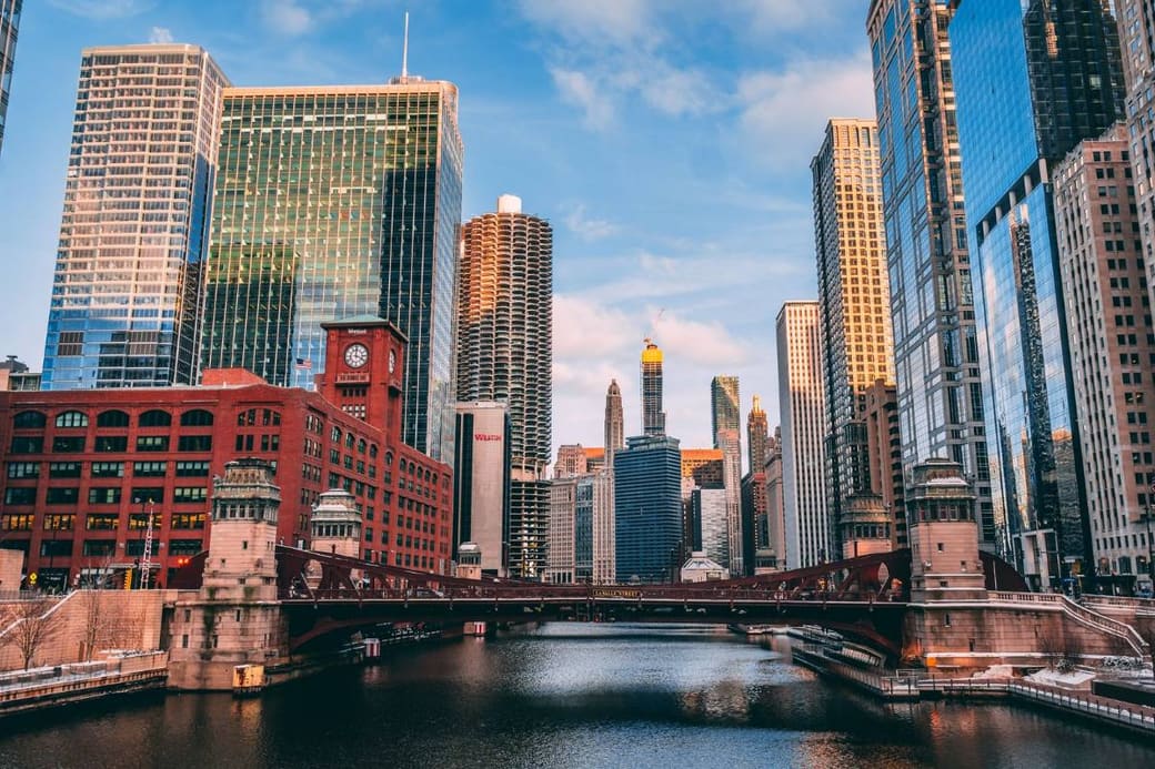 Glass towers crowding both banks of a river through a city center at sunset