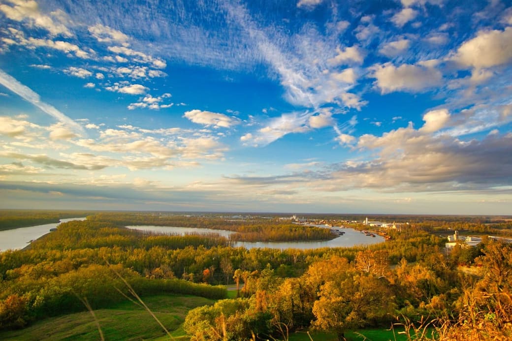 A wide river bending through flat wooded country at sunset, seen from the air