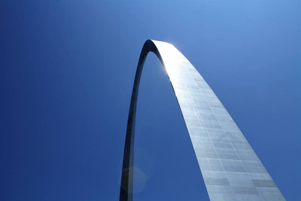 A stainless steel arch soaring against a clear blue sky, seen from directly beneath