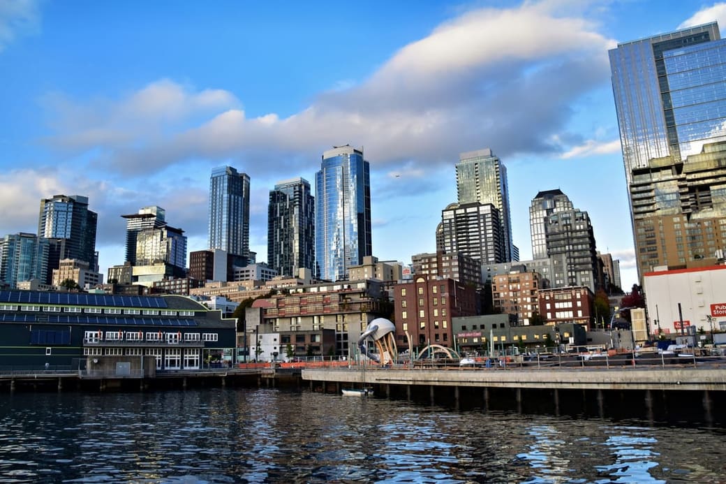 Glass towers along a working waterfront under a bright blue sky