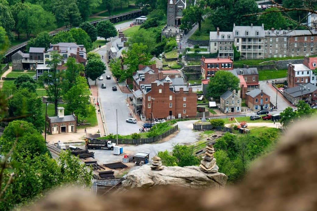 A small town of brick and stone buildings on a wooded hillside above a river bend